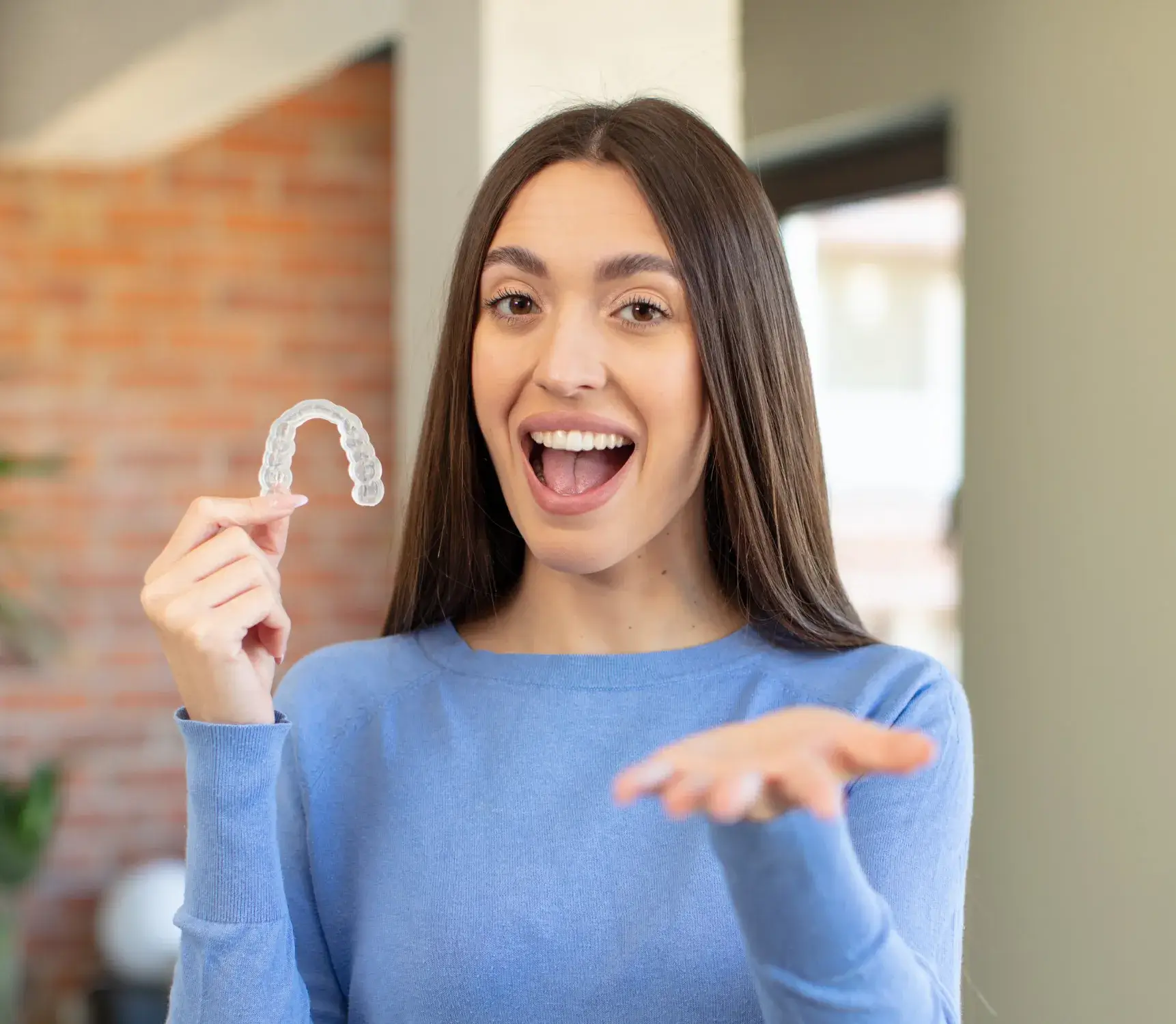 a woman holding up a fake tooth in front of her face