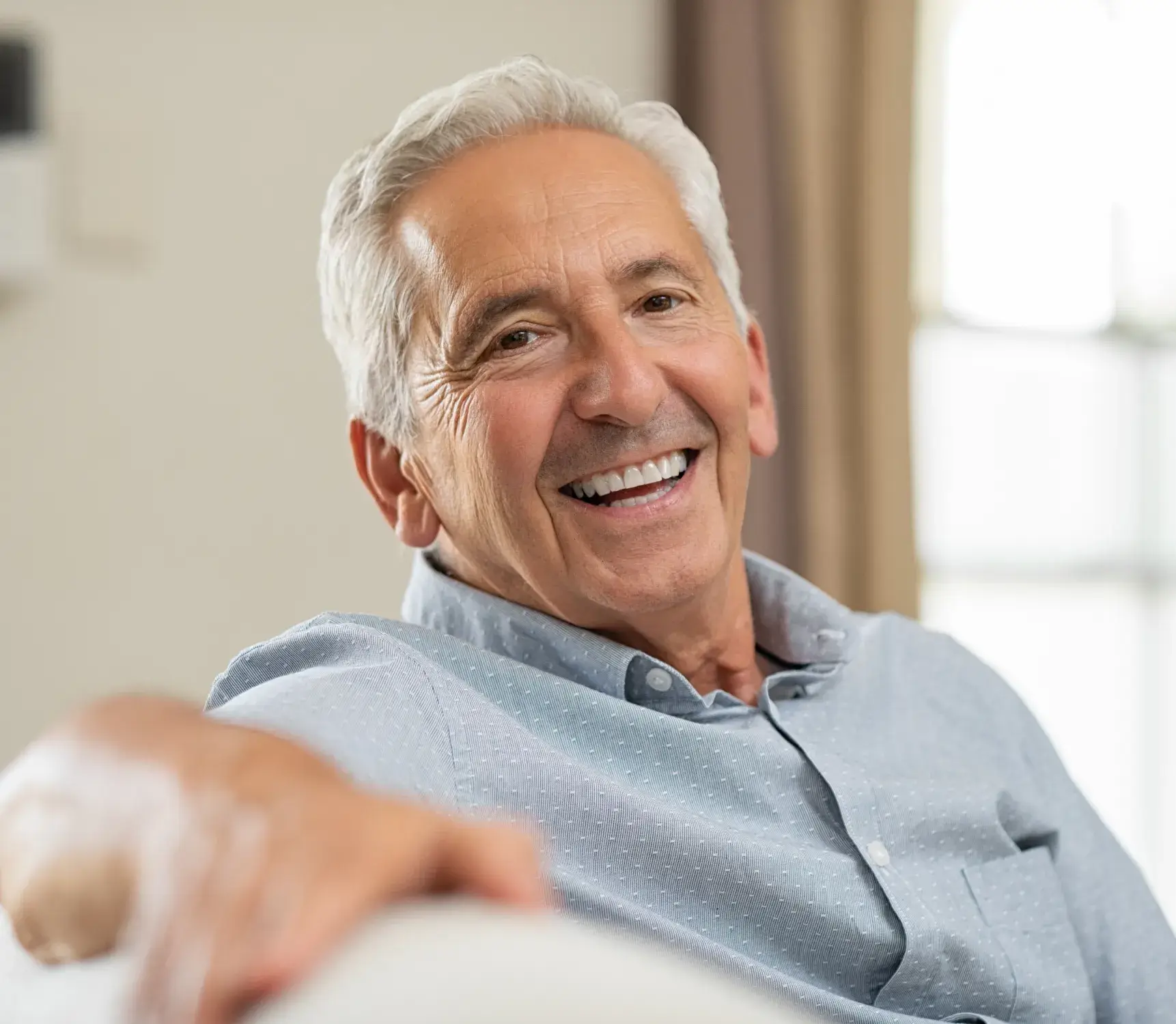 a man smiling while sitting on a couch