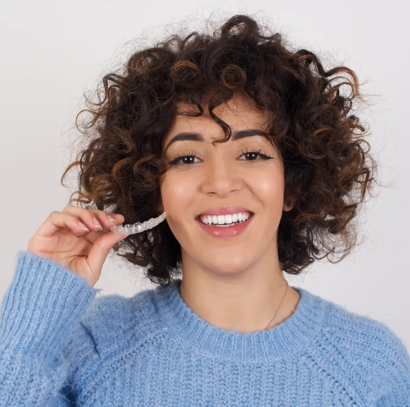 a woman smiling and holding a toothbrush in her mouth